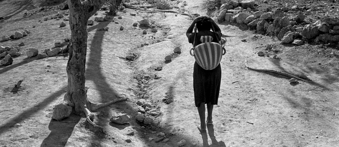 Después de sacar agua de un pozo profundo debajo del campamento y llenar jarras de agua, las mujeres caminan de regreso a sus casas. La Cieneguita. 1991.